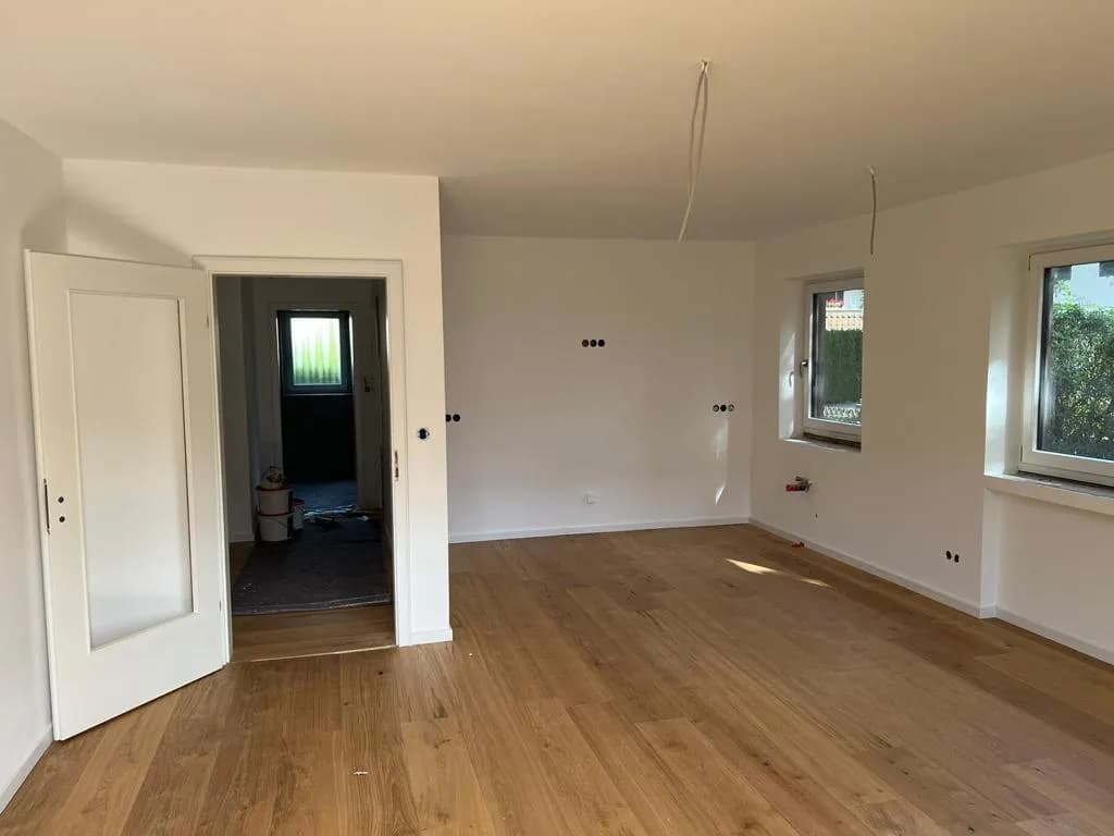 Wohnraum mit Holzboden und weißen Fenstern